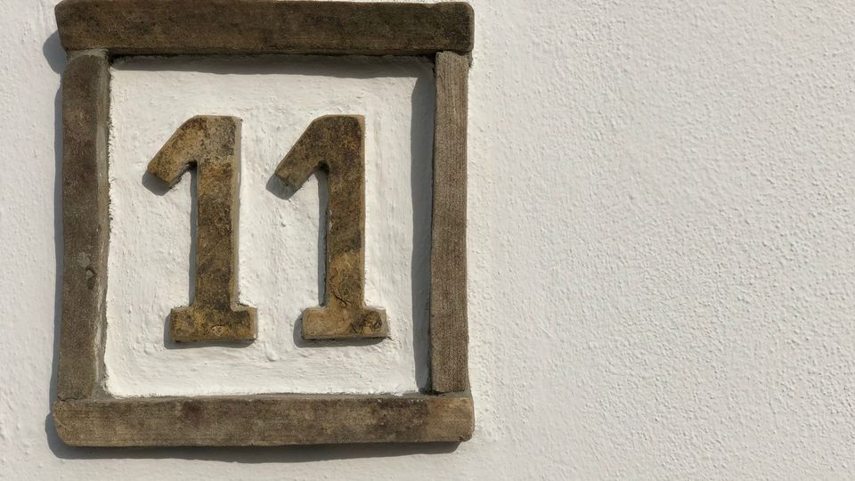 Ceramic house number 11 on a white wall