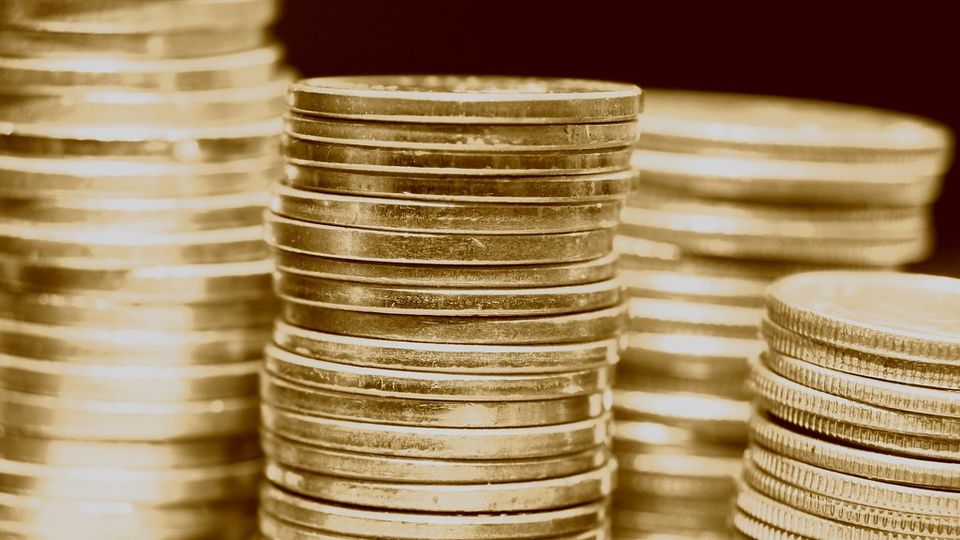 Tall stacks of gold-coloured coins on a dark table