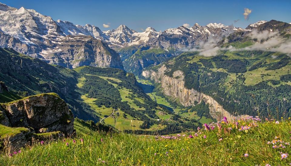 Deep green alpine valley below snow-capped mountains