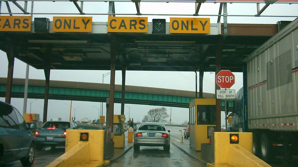 Cars queuing at automated toll booths on a highway, seen from the driver seat