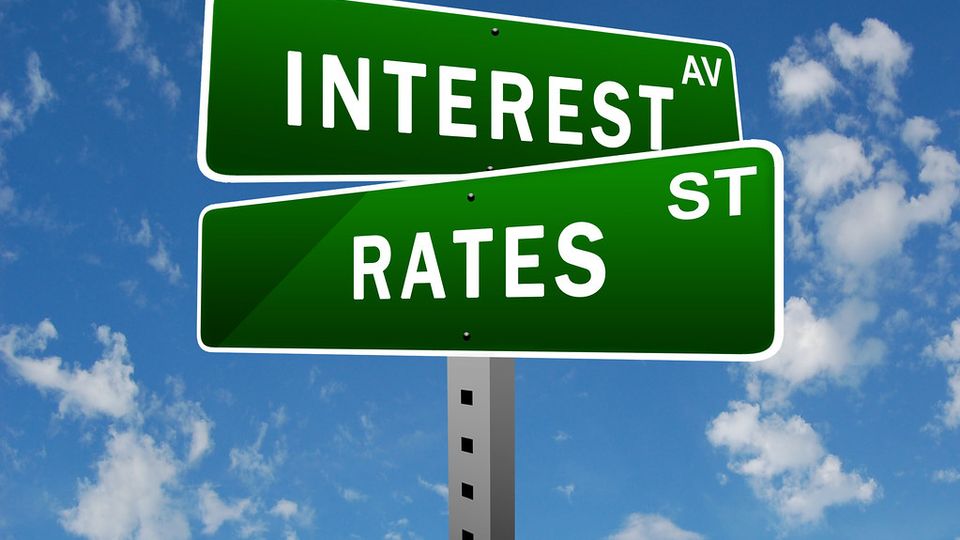 Green street signs reading Interest and Rates against a blue sky