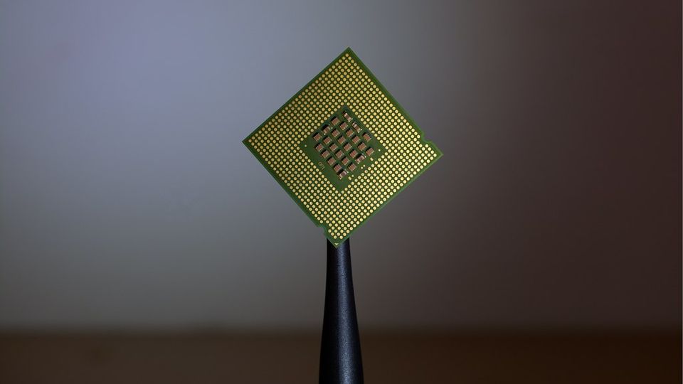 Computer processor chip held by tweezers