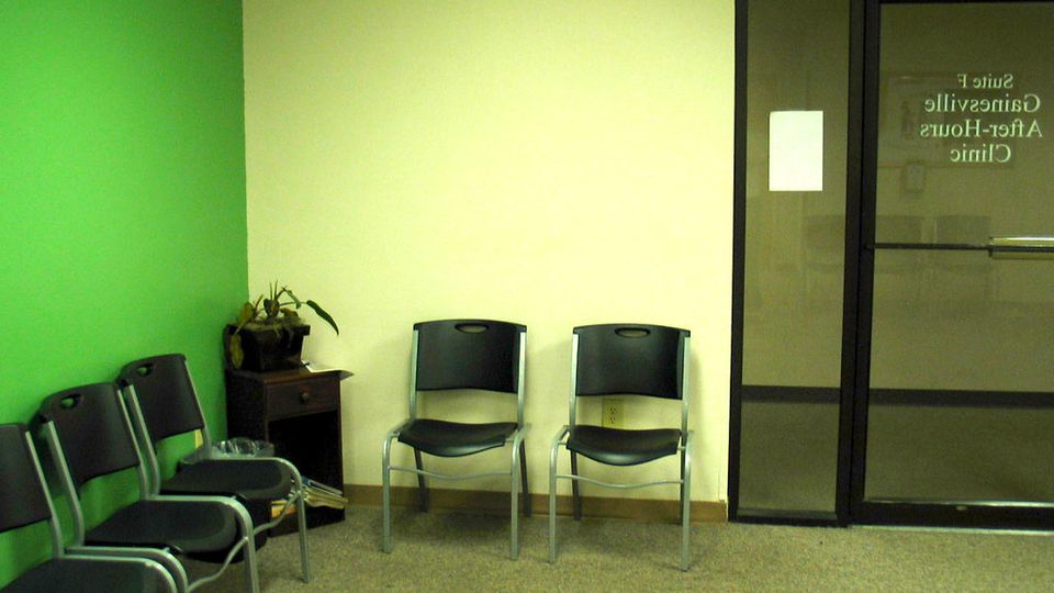 Empty chairs lined up along the wall of a waiting room