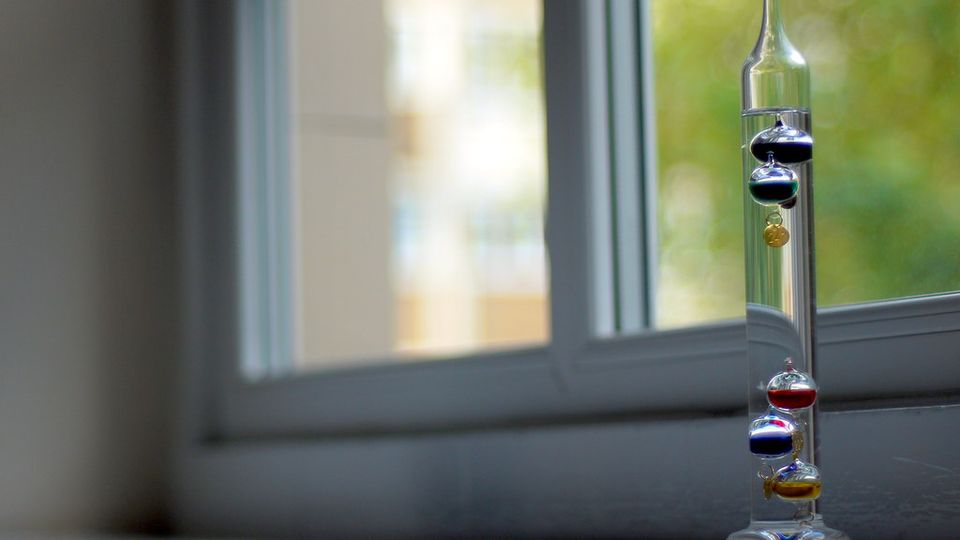 Galileo thermometer with coloured glass bulbs on a windowsill