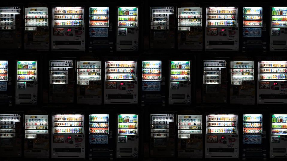 Rows of illuminated vending machines at night
