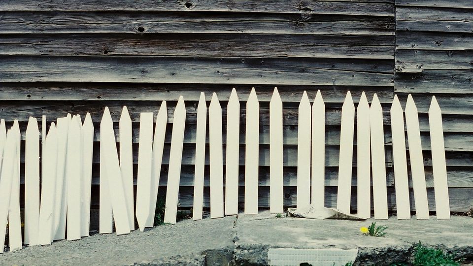 Row of sharpened wooden stakes leaning against a wall