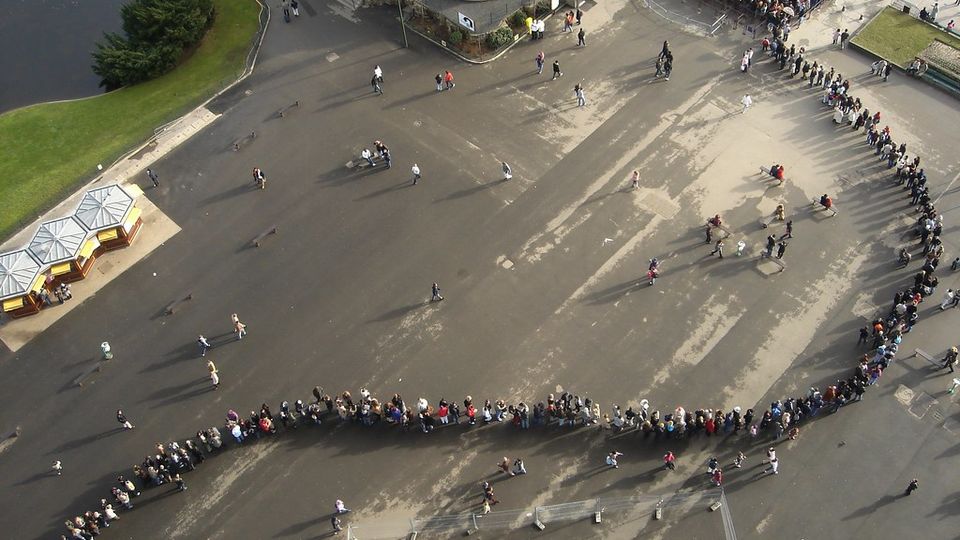 Aerial view of a long, winding queue of people on a plaza